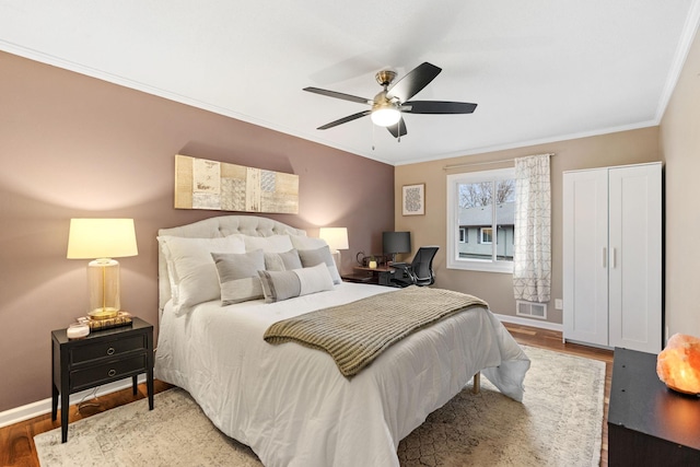 bedroom with visible vents, ornamental molding, baseboards, and wood finished floors