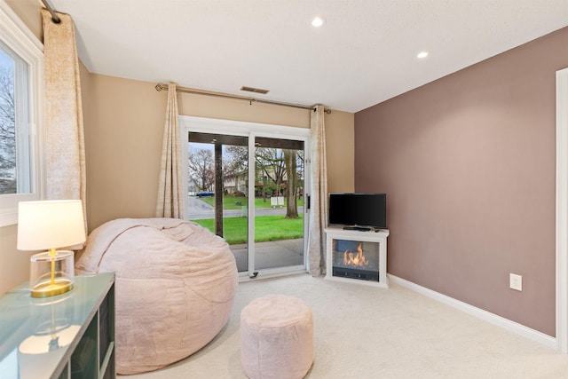 living area with carpet floors, recessed lighting, baseboards, and a glass covered fireplace