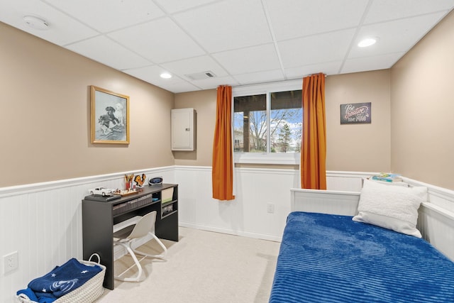 carpeted bedroom with visible vents, wainscoting, and a paneled ceiling