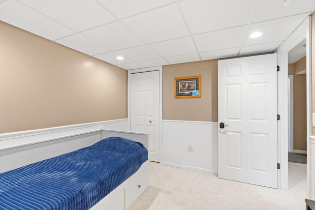 bedroom with a paneled ceiling, wainscoting, a closet, carpet, and recessed lighting