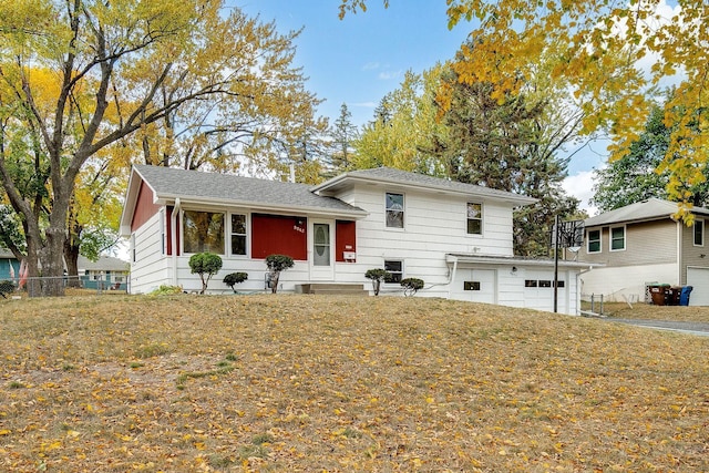 tri-level home featuring a garage, a front lawn, and fence