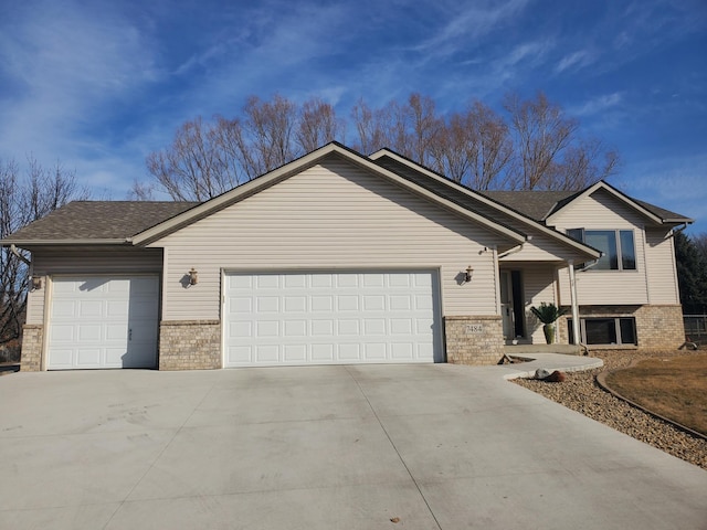 tri-level home with a garage, brick siding, driveway, and a shingled roof