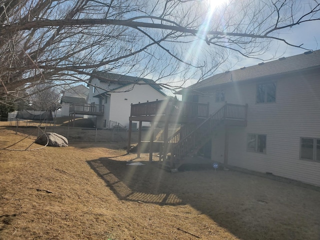 back of property with stairs, a trampoline, fence, and a wooden deck