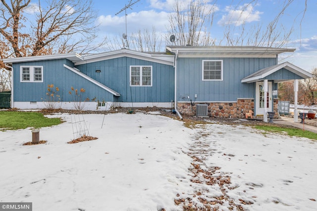 view of front facade with crawl space, stone siding, and central AC unit