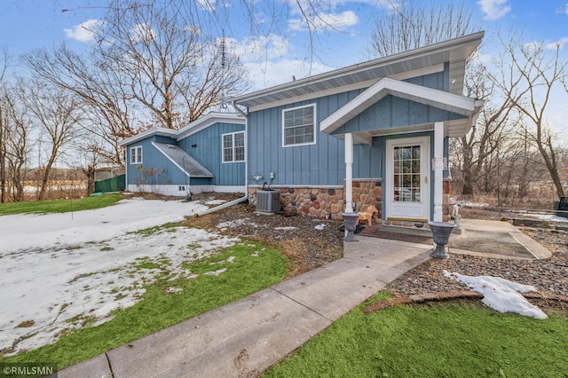 view of front of property with stone siding, cooling unit, and board and batten siding