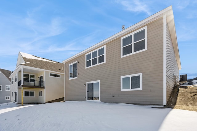 snow covered property with central AC unit and a balcony