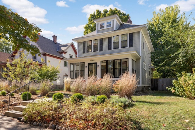 american foursquare style home with a front lawn and fence