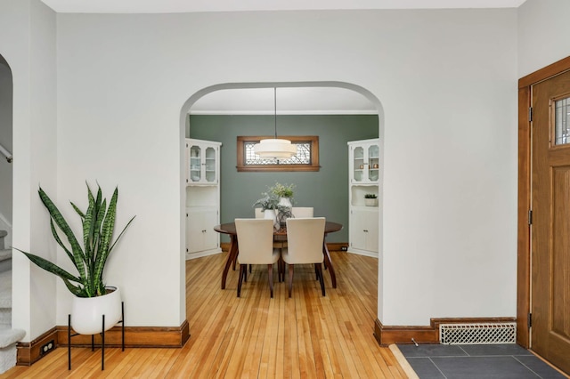 dining area with arched walkways, visible vents, light wood-style flooring, and stairs