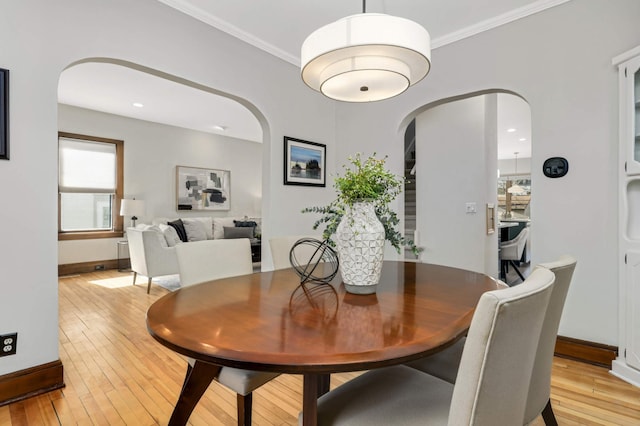 dining room featuring crown molding, light wood-type flooring, and baseboards