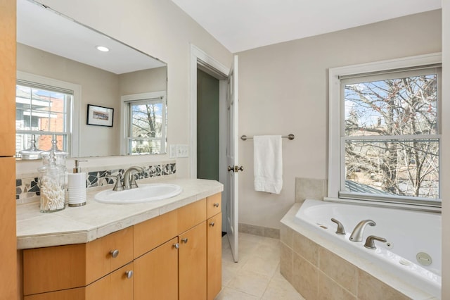 full bathroom featuring a jetted tub, vanity, and tile patterned flooring