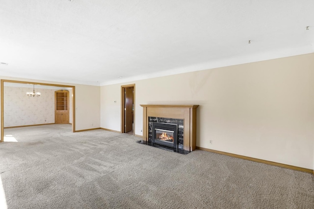 unfurnished living room with baseboards, light carpet, a chandelier, and a fireplace