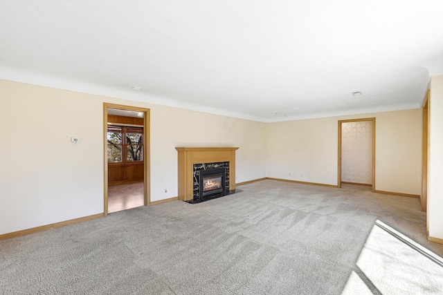 unfurnished living room with light colored carpet, baseboards, and a premium fireplace