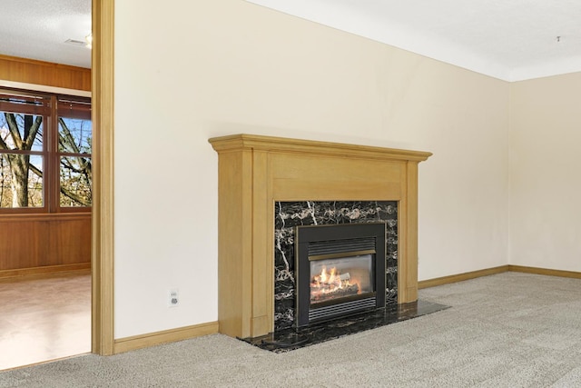 interior details featuring a high end fireplace, baseboards, wood walls, and carpet flooring