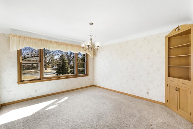 empty room with a notable chandelier, wallpapered walls, baseboards, and carpet floors