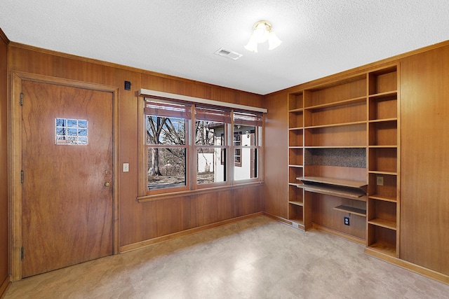 interior space featuring visible vents, wood walls, and a textured ceiling