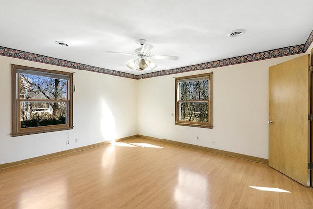 spare room with light wood finished floors, visible vents, and baseboards