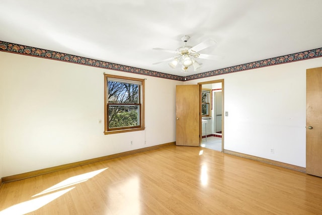 spare room with light wood finished floors, ceiling fan, and baseboards