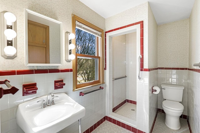 bathroom featuring a sink, a wainscoted wall, toilet, and wallpapered walls