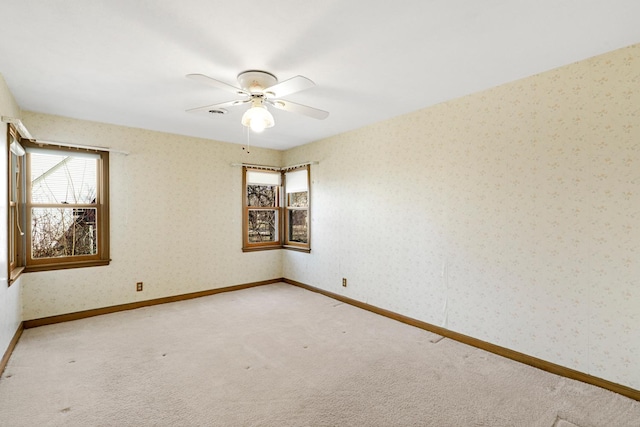 carpeted spare room with wallpapered walls, a ceiling fan, and baseboards