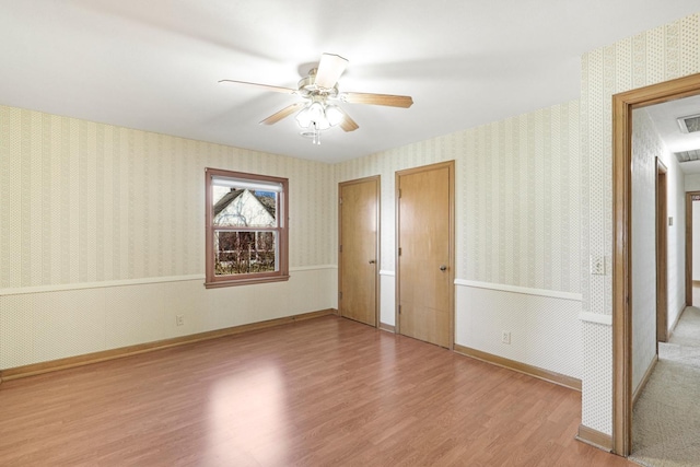 unfurnished bedroom featuring wallpapered walls, baseboards, and wood finished floors