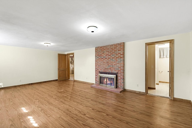 unfurnished living room with light wood-type flooring, baseboards, and a fireplace