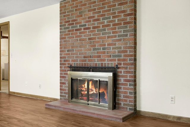 interior details featuring a fireplace, baseboards, and wood finished floors