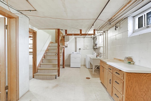 basement with stairway, light floors, separate washer and dryer, concrete block wall, and a sink