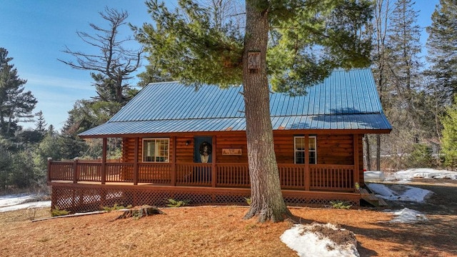 rear view of house with covered porch, log exterior, and metal roof