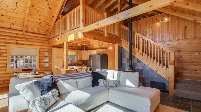 living room with stairway, beamed ceiling, wooden ceiling, a wood stove, and high vaulted ceiling