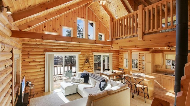 living room featuring beamed ceiling, high vaulted ceiling, light wood-style flooring, wood ceiling, and a wood stove