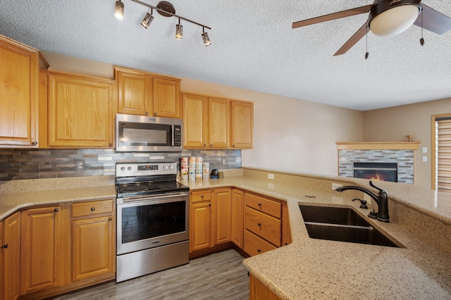 kitchen featuring sink, kitchen peninsula, appliances with stainless steel finishes, and light stone countertops