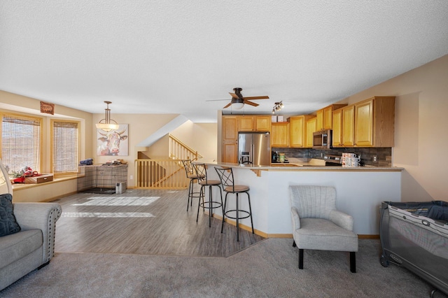 kitchen featuring appliances with stainless steel finishes, a breakfast bar, pendant lighting, and kitchen peninsula