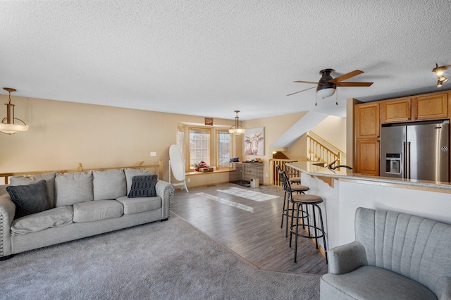 living room with ceiling fan, light wood-type flooring, and a textured ceiling