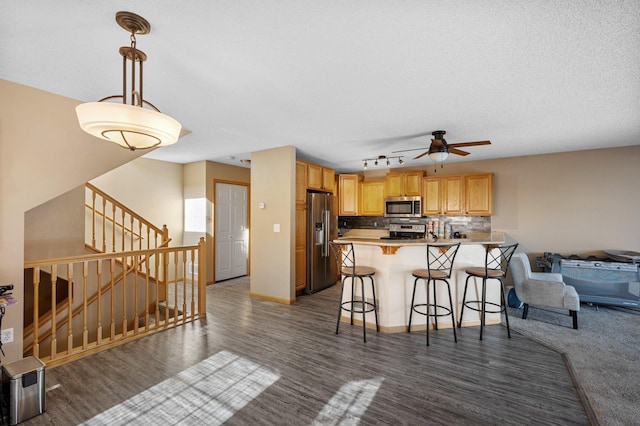 kitchen featuring appliances with stainless steel finishes, dark wood-type flooring, a breakfast bar area, and kitchen peninsula