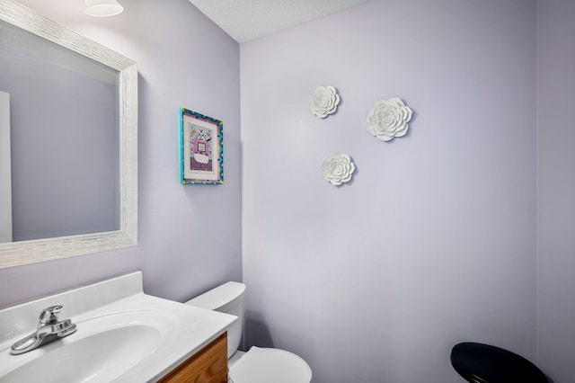 bathroom featuring a textured ceiling, toilet, and vanity