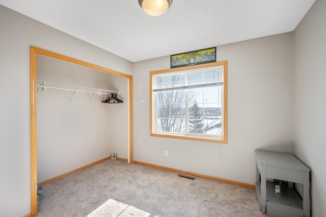 unfurnished bedroom featuring a textured ceiling, light carpet, and a closet