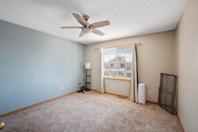 carpeted empty room with ceiling fan and a textured ceiling