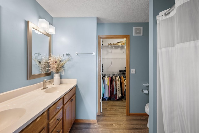 bathroom with curtained shower, vanity, a textured ceiling, toilet, and hardwood / wood-style flooring