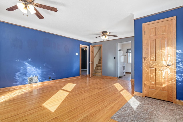 empty room with stairway, baseboards, visible vents, and wood finished floors