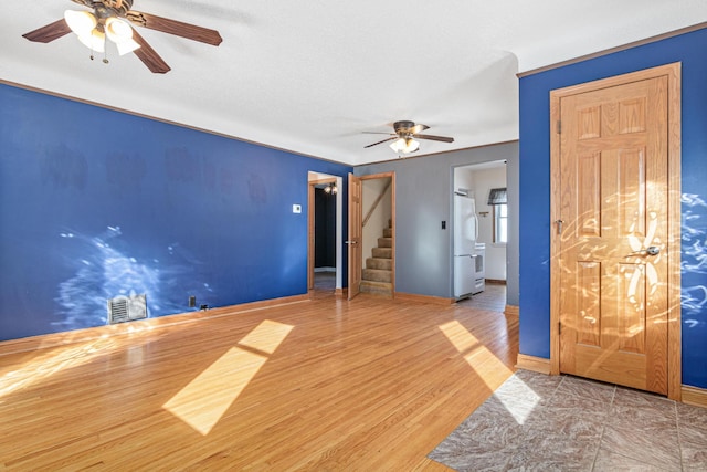 empty room with stairway, wood finished floors, visible vents, and baseboards