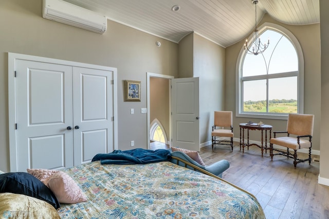 bedroom with a notable chandelier, lofted ceiling, hardwood / wood-style floors, a wall mounted AC, and baseboards