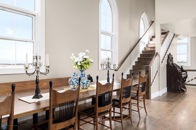 dining room featuring stairs, a towering ceiling, baseboards, and wood finished floors