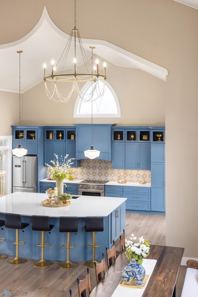 kitchen with blue cabinetry, glass insert cabinets, high quality appliances, and a kitchen breakfast bar