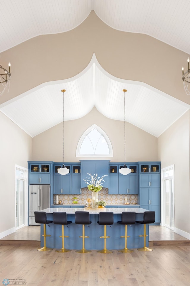 kitchen featuring a kitchen bar, glass insert cabinets, high end refrigerator, and blue cabinetry