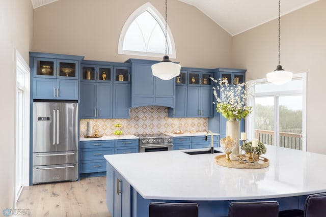 kitchen featuring light countertops, appliances with stainless steel finishes, a sink, and blue cabinets