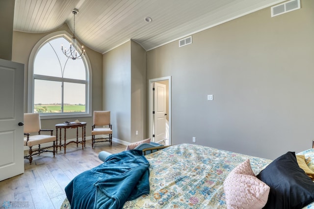 bedroom featuring lofted ceiling, a chandelier, visible vents, and light wood-style floors