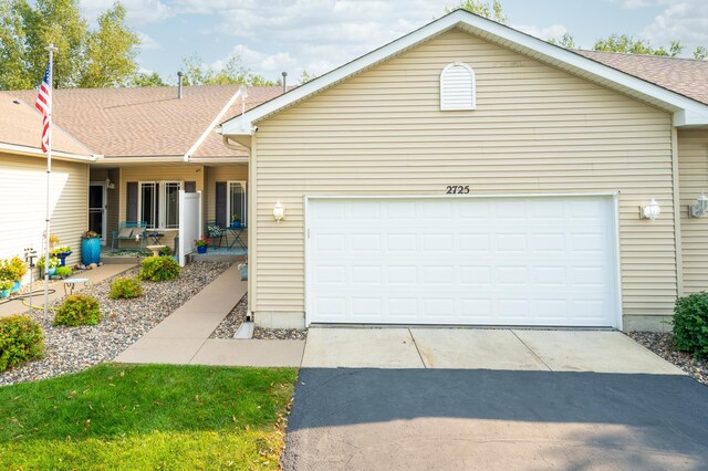 ranch-style house featuring a garage, concrete driveway, a porch, and roof with shingles