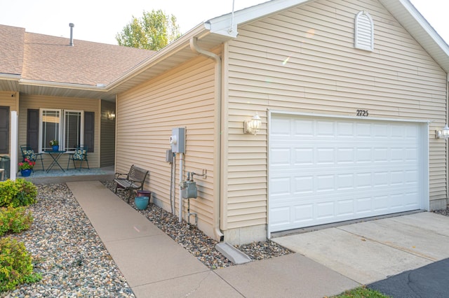 view of home's exterior featuring concrete driveway, a porch, and roof with shingles