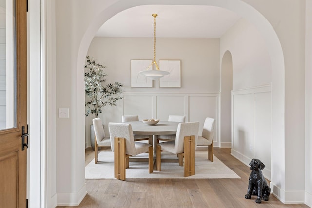 5455 Rolling Hills Pkwy, Victoria, MN 55318 - dining space featuring arched walkways, a decorative wall, light wood-style floors, and wainscoting