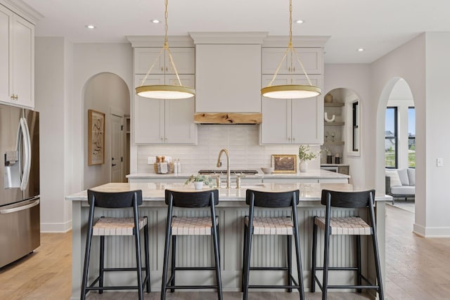 5455 Rolling Hills Pkwy, Victoria, MN 55318 - kitchen with stainless steel appliances, decorative backsplash, a kitchen island with sink, light wood finished floors, and recessed lighting